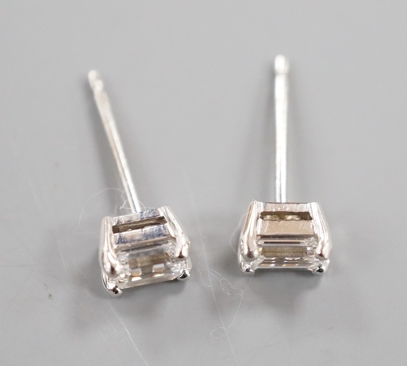 A modern pair of 750 white metal and emerald cut solitaire diamond ear studs, gross weight 1.4 grams